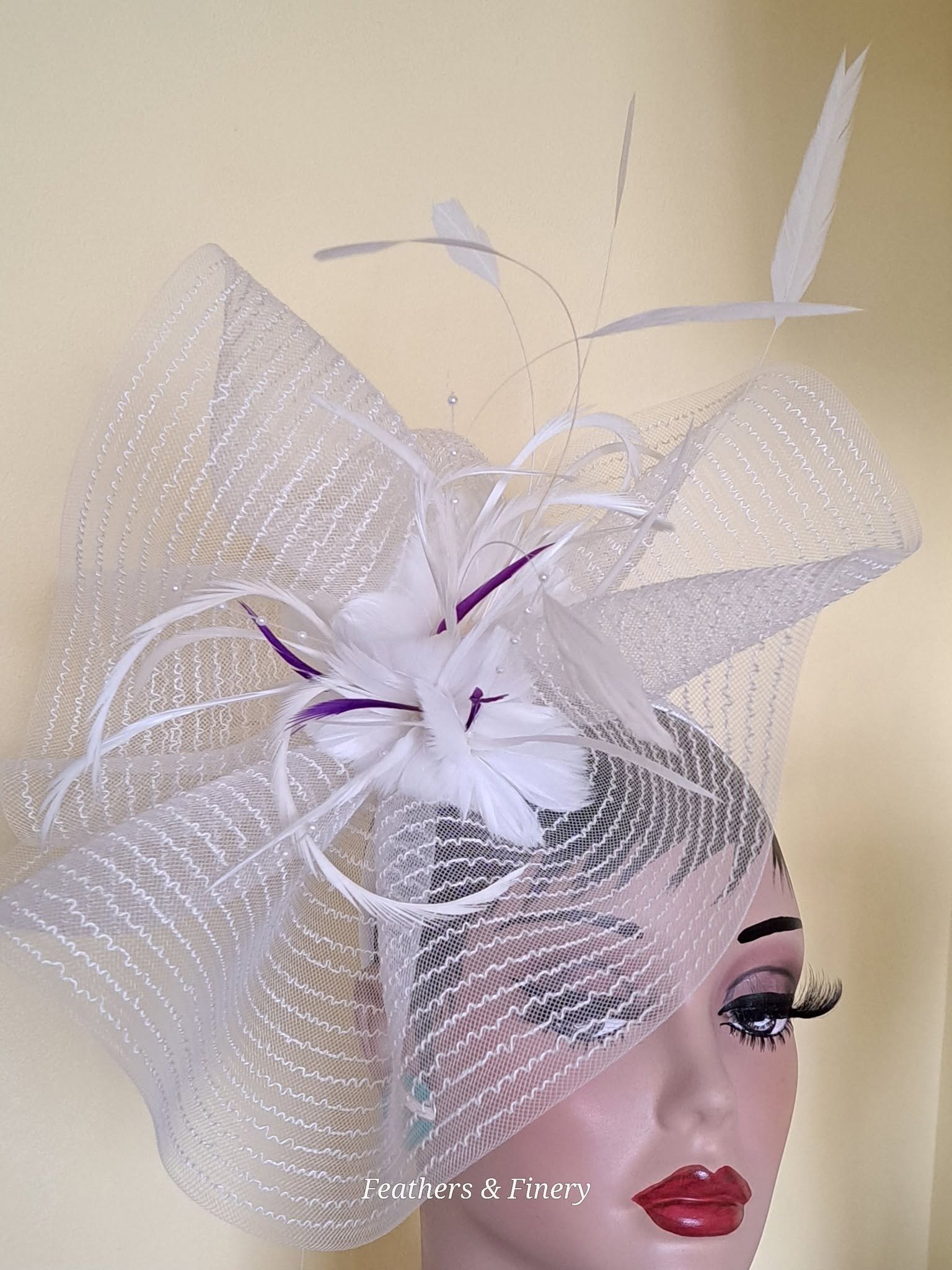 White fascinator with purple flower and feather details